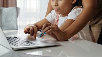 child and helper at a laptop