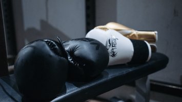 black, white and god boxing gloves on a weights bench