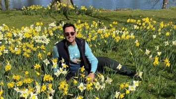Tom sits in a grassy area surrounded by daffodils