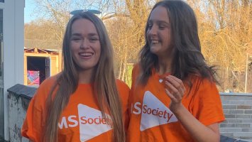 The photo shows Mia and her friend wearing orange MS Society t-shirts. They're standing side-by-side and smiling at the camera.