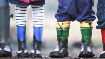 Four children are standing in a row while wearing wellies 