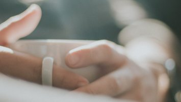 The photo shows a person's hands holding a white mug