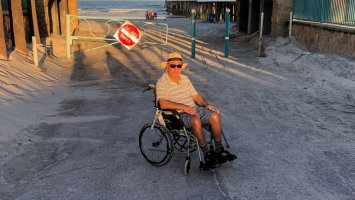 The photo shows Kanti sitting in a wheelchair on holiday