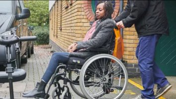 Woman with MS in wheelchair by a car