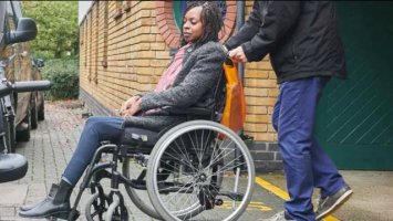 Woman in wheelchair next to a car
