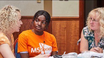 A group of people sitting round a table sharing their MS stories