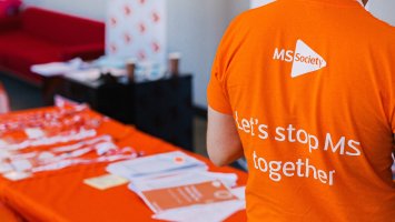 Back of person wearing MS Society t-shirt and table with branded materials