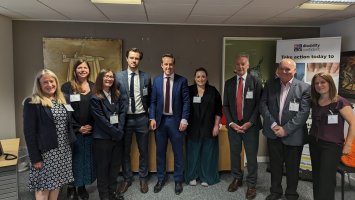 Tom Purseglove, MP, stands in an office flanked with representatives from leading UK MS charities