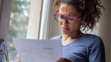 A woman reading a bill looking concerned