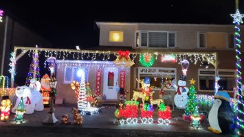 A house at night with a garden full of large illuminated Christmas ornaments 