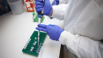 Close up of blue-gloved hands working in a lab