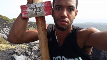 Stefan Taylor taking a selfie next to a sign showing how high he's hiked