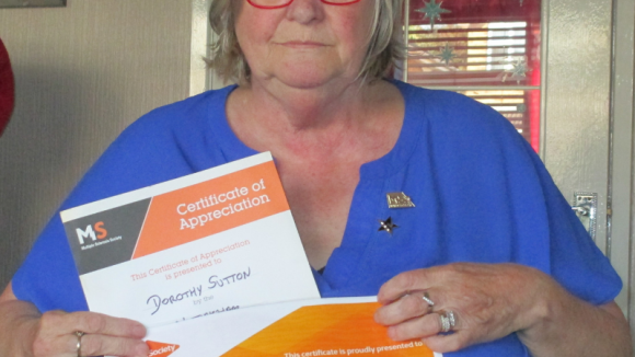 Dorothy Sutton sits holding her two Shining Star award certificates