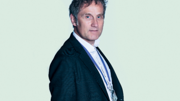 Professor Klaus Schmierer standing against a pale blue background