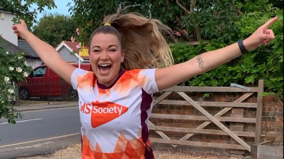 Woman in MS Society t-shirt smiling with her hands in the air