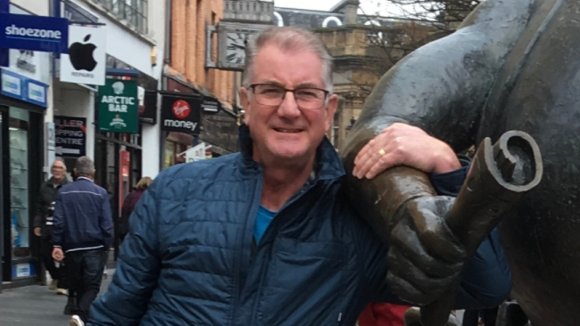 clive pictured in Dundee, holding the arm of the Desperate Dan statue