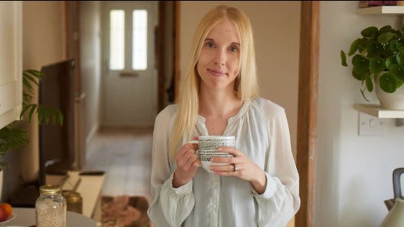 A woman in a kitchen holding a mug