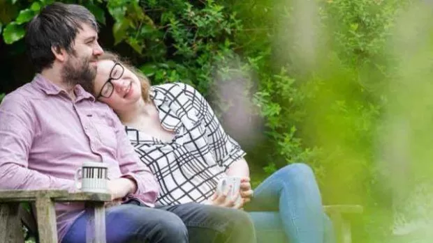 Photo: Young couple sat on bench in garden