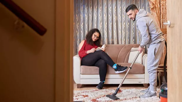 Photo: Man with MS at home doing the hoovering