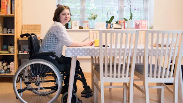 a woman sat in a wheelchair at a kitchen table