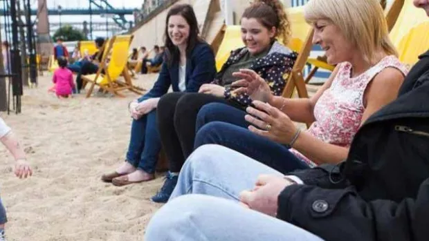 a photo of a family sat in deck chairs on a beach