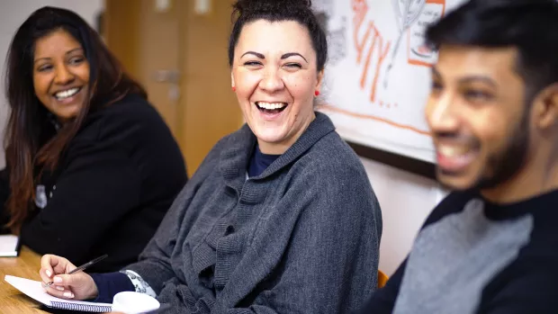 Human Resources Officer in a meeting laughing with colleagues to camera