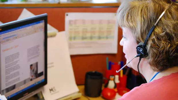 photo: a woman with a telephone headset working on the MS helpline