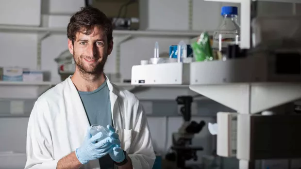 Photo: Researcher working in the lab and smiling at the camera