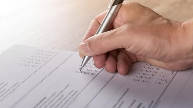 Photo: a hand filling out a form with a pen