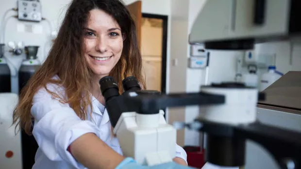 Photo: a scientist with a microscope she is smiling