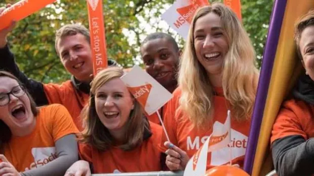 Photo shows a group of cheerers at an MS Society cheering station waving flags
