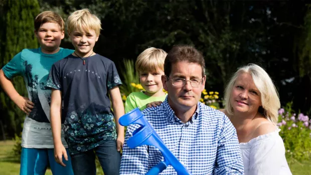 Photo: Man with MS in the garden with his three young boys and his wife