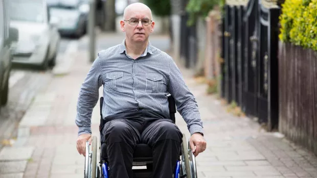 a photo of a man in a wheelchair going down a street