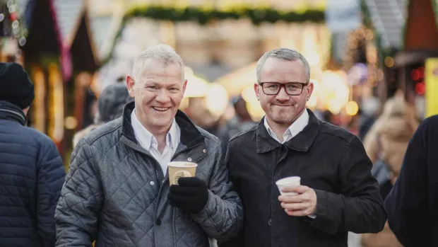 a photo of two men outside holding coffee cup