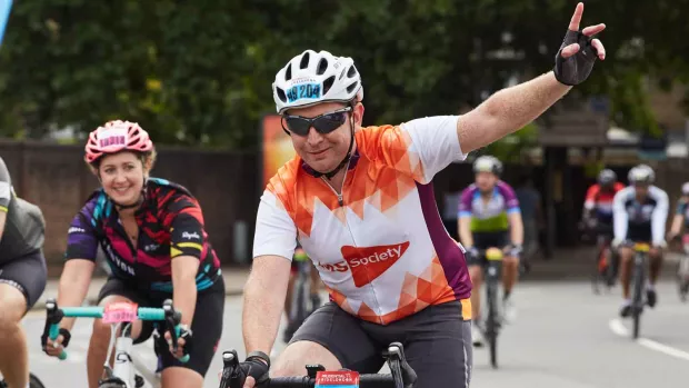 Photo: A fundraiser on a bike event with his arm held high waving