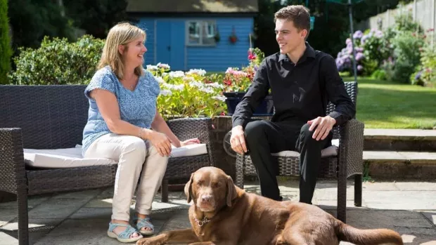 Woman with MS sits in garden with son and pet dog