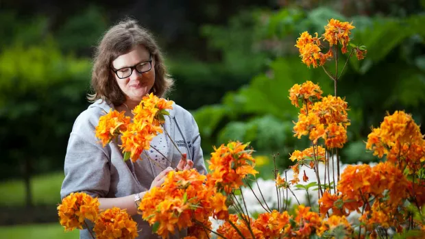 a photo of a woman in a garden stood near some orange flowers