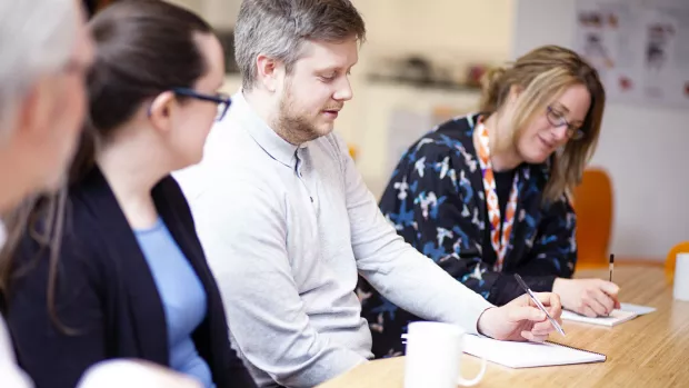 Photo: A group of people in a meeting taking notes