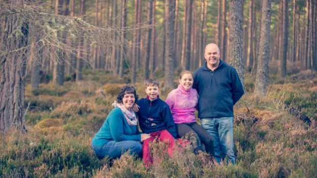 Gail with her two children and husband, pictured in a forest.