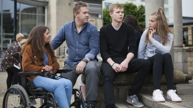 A group of people sit beside some steps, chatting.