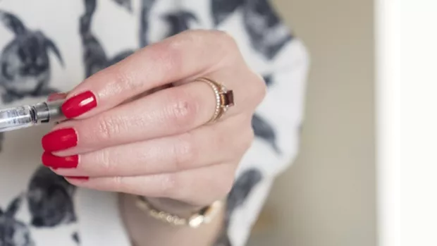 Photo: Kirsty's hands with red nails holding her MS treatment