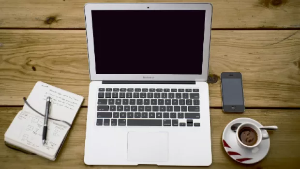 Photo: a Laptop, notebook and coffee cup on a desk