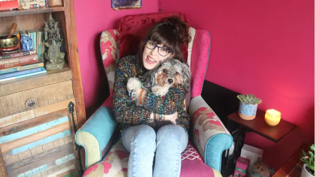 LLiz sits on an armchair hugging Artie the dog