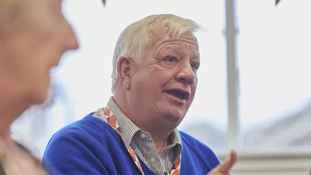 Man wearing blue jumper talking and gesticulating with his hands