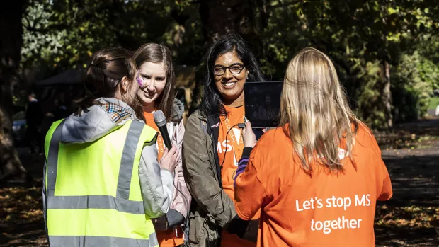 Photo: Two people with their backs to us interview two girls at MS Walk