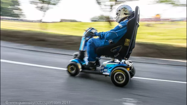 Noel racing his scooter with countryisde in the background