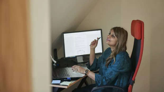 A woman sits at her computer, looking thoughtful.