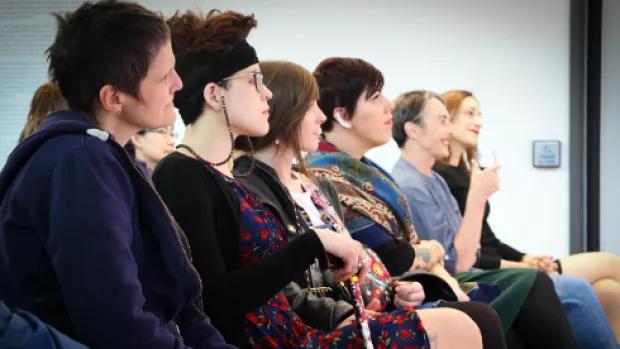 Photo: a group of people sitting in a row of chairs listening to a talk