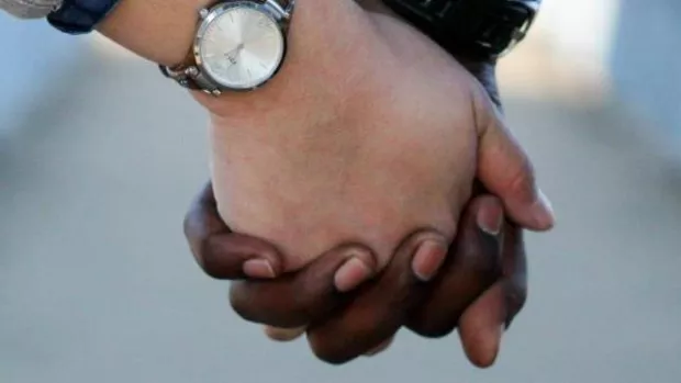 A close-up photo of a couple holding hands, showing people need support when managing MS relapses.