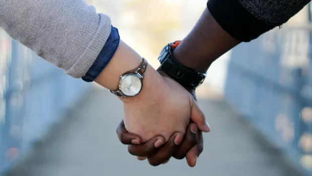Image shows close up of a couple holding hands